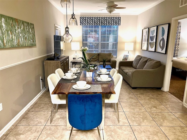 tiled dining space featuring ceiling fan and crown molding