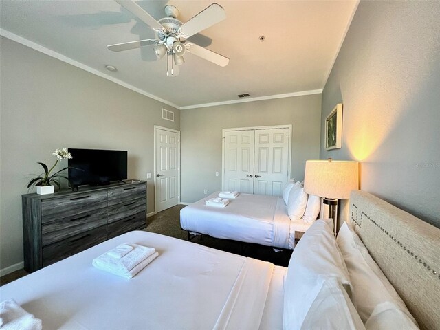 bedroom with carpet, ornamental molding, ceiling fan, and a closet