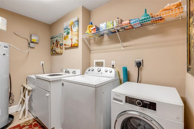 washroom featuring water heater, washer and dryer, and a sink