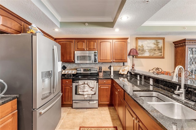 kitchen with ornamental molding, appliances with stainless steel finishes, a tray ceiling, and a sink