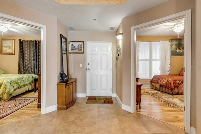 foyer featuring light tile patterned floors, visible vents, baseboards, and ceiling fan