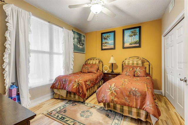 bedroom featuring visible vents, ceiling fan, baseboards, wood finished floors, and a closet