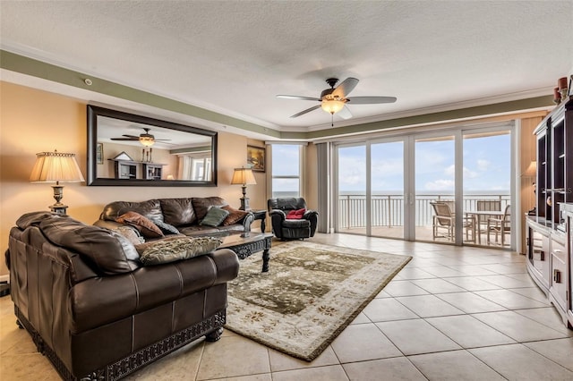 living room featuring ceiling fan, ornamental molding, light tile patterned flooring, and a textured ceiling