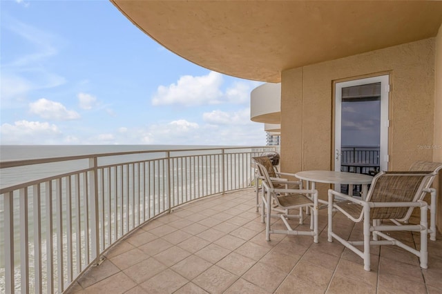 balcony with outdoor dining space and a water view