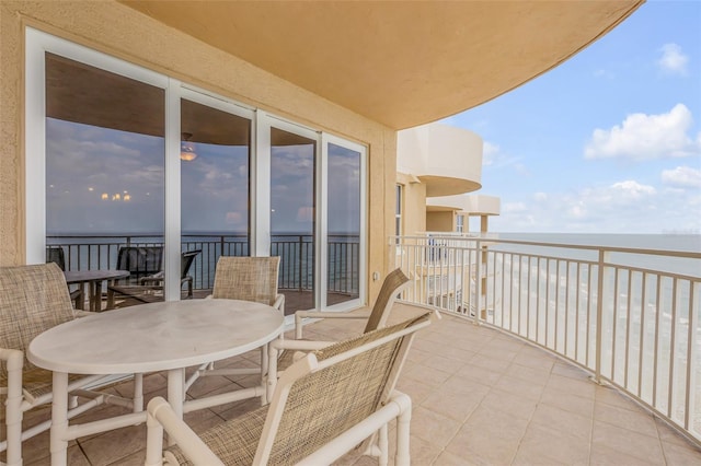 balcony with a water view and outdoor dining space