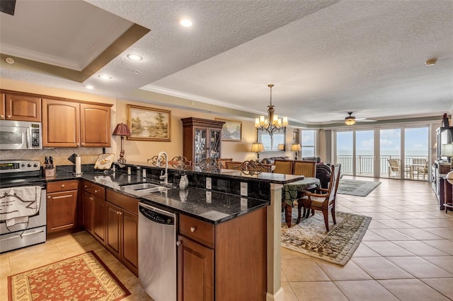 kitchen featuring a sink, open floor plan, appliances with stainless steel finishes, a peninsula, and a raised ceiling