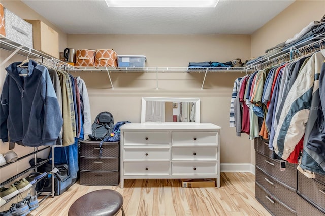 walk in closet with light wood finished floors