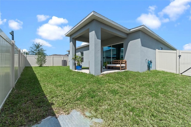 rear view of house with cooling unit, a yard, and a patio area