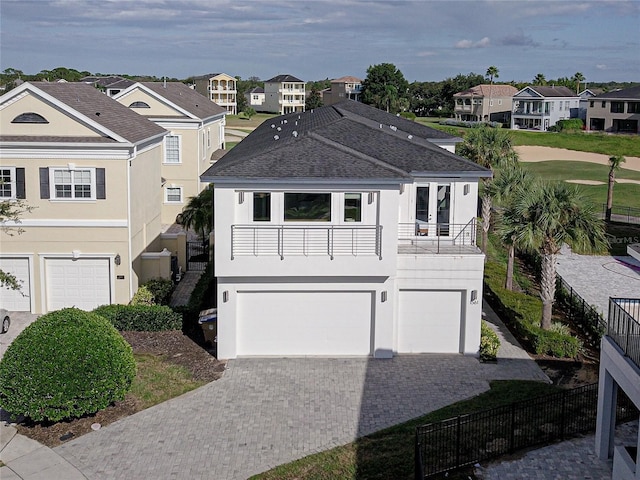 view of front of property featuring stucco siding, an attached garage, driveway, and a residential view