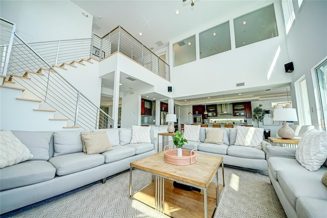 living room with stairway, a towering ceiling, and visible vents