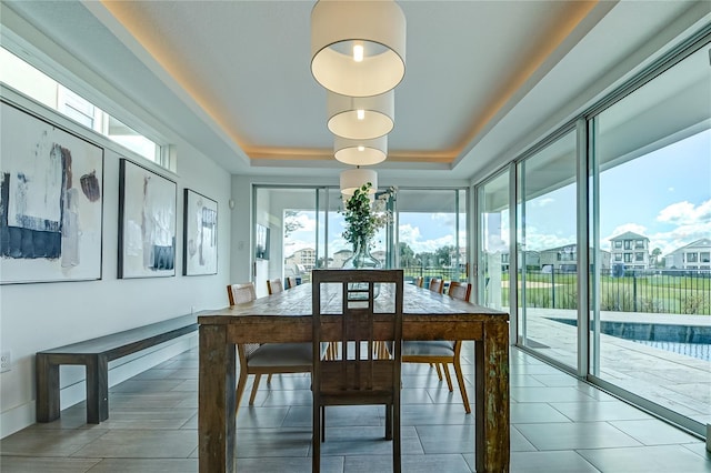 tiled dining space with a tray ceiling