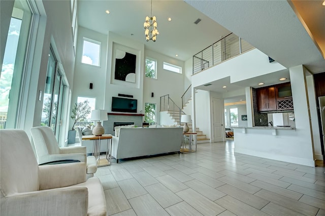 living room with a towering ceiling, visible vents, a notable chandelier, stairs, and a fireplace