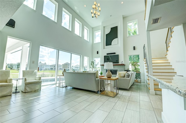 living area featuring visible vents, a high ceiling, a chandelier, and stairway