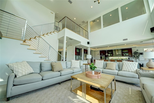 living area with a towering ceiling, stairs, and visible vents
