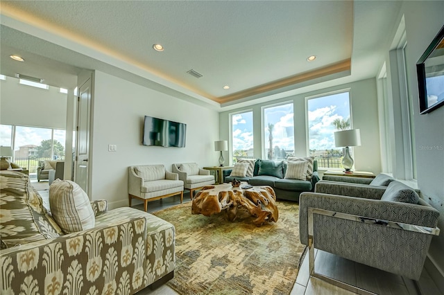 living area with recessed lighting, a raised ceiling, visible vents, and baseboards