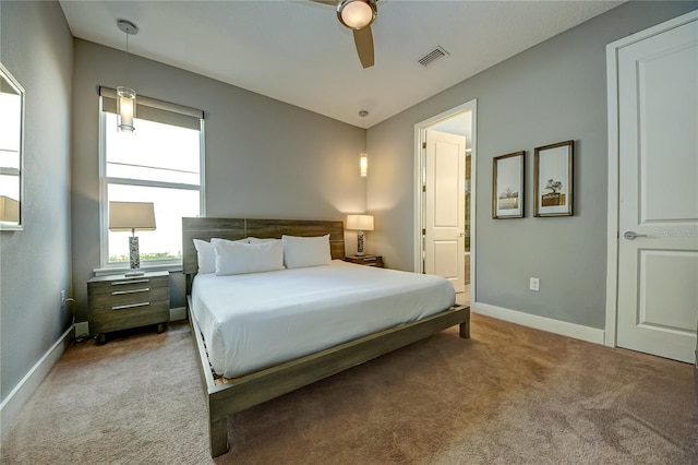 carpeted bedroom featuring ensuite bath, baseboards, a ceiling fan, and visible vents