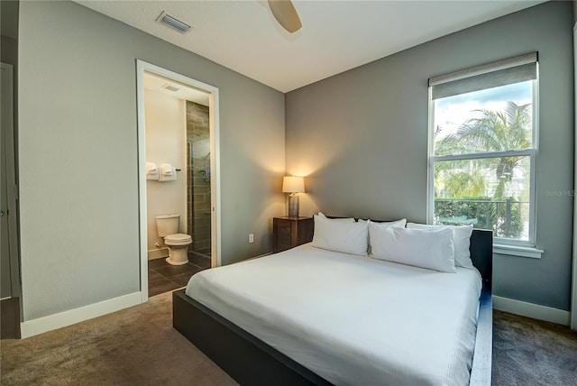 carpeted bedroom featuring ceiling fan, multiple windows, and ensuite bath