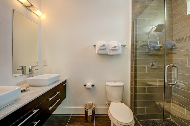 bathroom with a sink, double vanity, toilet, baseboards, and a shower stall