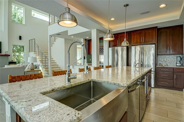 kitchen featuring light stone countertops, appliances with stainless steel finishes, sink, a kitchen breakfast bar, and pendant lighting