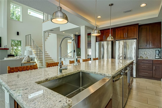 kitchen with backsplash, a healthy amount of sunlight, appliances with stainless steel finishes, and a sink