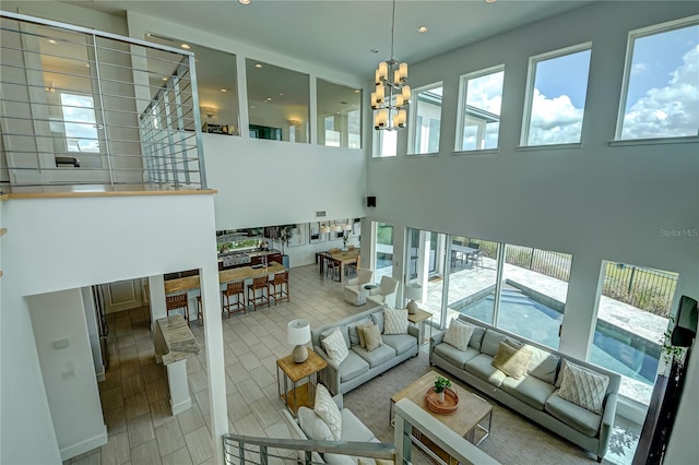 living room featuring a towering ceiling, an inviting chandelier, and recessed lighting