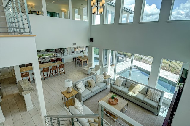 living room featuring a chandelier, a healthy amount of sunlight, a towering ceiling, and visible vents