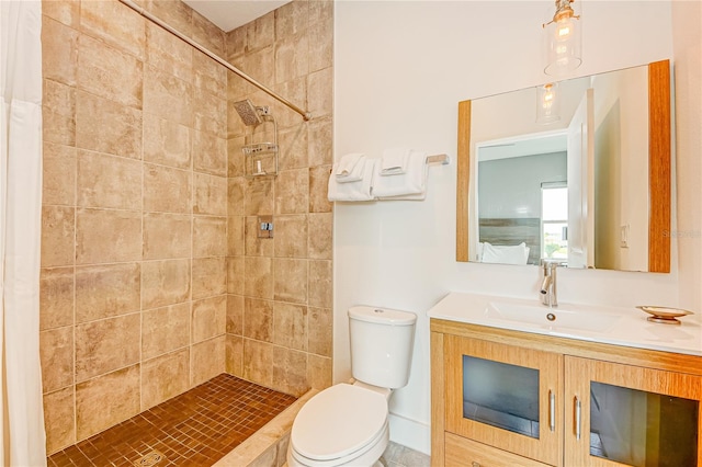 bathroom featuring a tile shower, toilet, and vanity