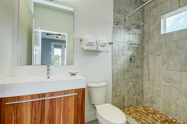 bathroom with vanity, tiled shower, toilet, and ceiling fan