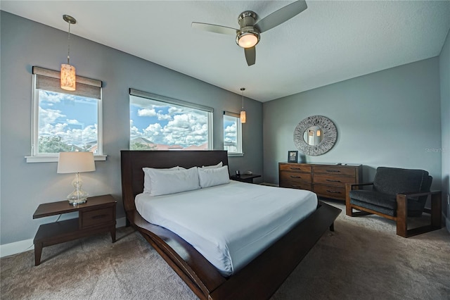 carpeted bedroom featuring multiple windows and ceiling fan