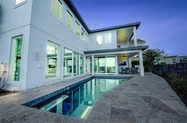 rear view of house with a fenced in pool, fence, a patio area, a balcony, and stucco siding