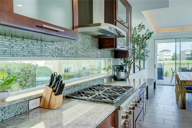 kitchen featuring gas stove, light stone countertops, ventilation hood, and plenty of natural light