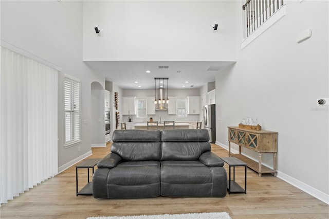 living room with light wood-type flooring and a high ceiling