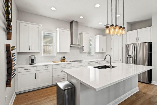 kitchen with white cabinets, stainless steel fridge, sink, wall chimney range hood, and light hardwood / wood-style floors