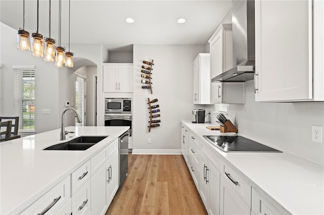 kitchen featuring wall chimney exhaust hood, white cabinetry, sink, and stainless steel appliances