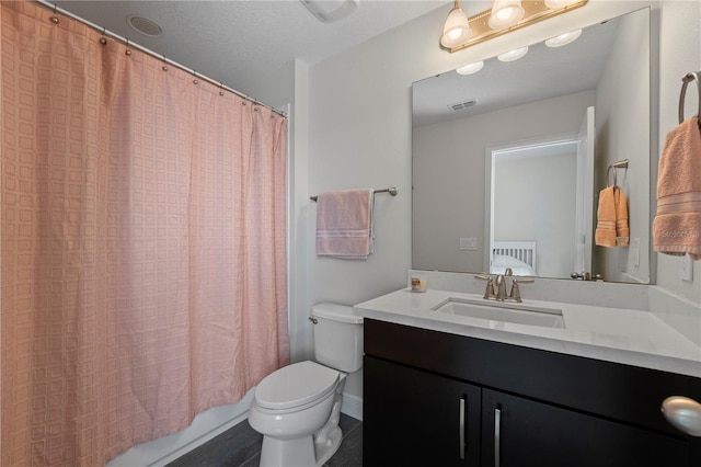 bathroom with a textured ceiling, vanity, and toilet