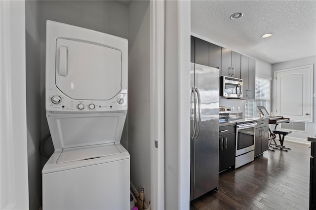 laundry room with a textured ceiling, stacked washer / drying machine, and dark hardwood / wood-style flooring