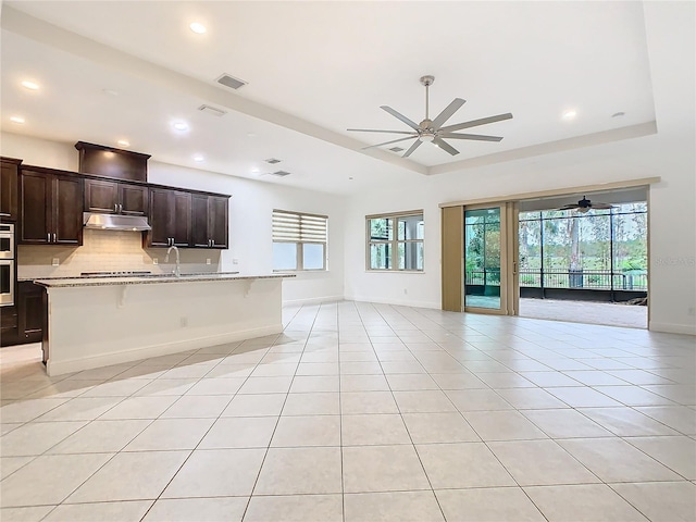 kitchen with tasteful backsplash, visible vents, open floor plan, light tile patterned flooring, and under cabinet range hood