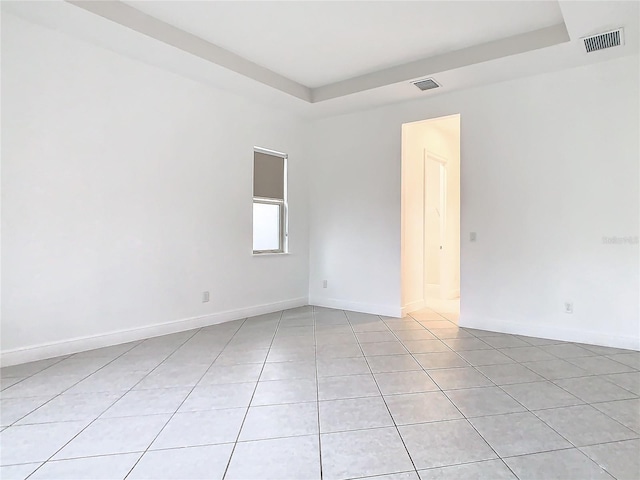 spare room with a raised ceiling, visible vents, baseboards, and light tile patterned floors