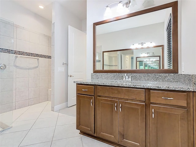 full bath with a tile shower, vanity, and tile patterned floors