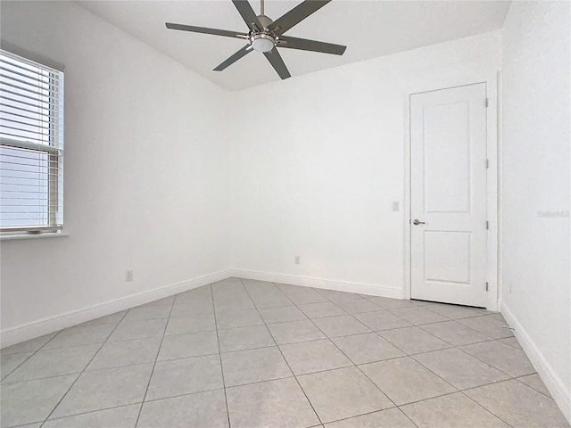 empty room with baseboards, a ceiling fan, and light tile patterned flooring