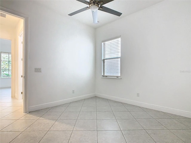 empty room featuring light tile patterned floors, plenty of natural light, and baseboards