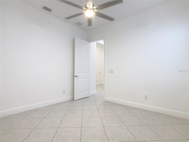 spare room featuring baseboards, visible vents, a ceiling fan, and light tile patterned flooring