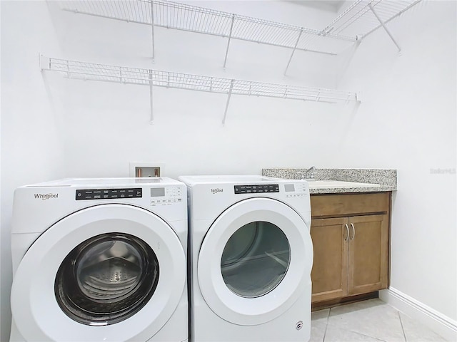 clothes washing area with light tile patterned floors, cabinet space, baseboards, independent washer and dryer, and a sink