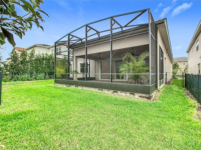 rear view of property featuring a yard, a fenced backyard, a ceiling fan, and a lanai