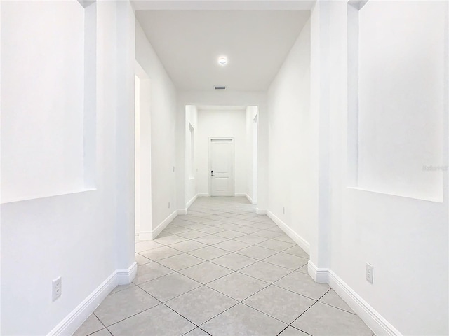 hall featuring visible vents, baseboards, and light tile patterned flooring