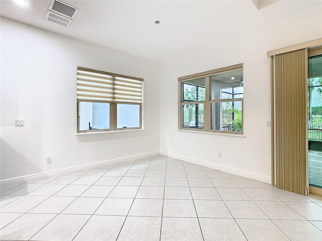 spare room featuring light tile patterned floors, visible vents, and baseboards