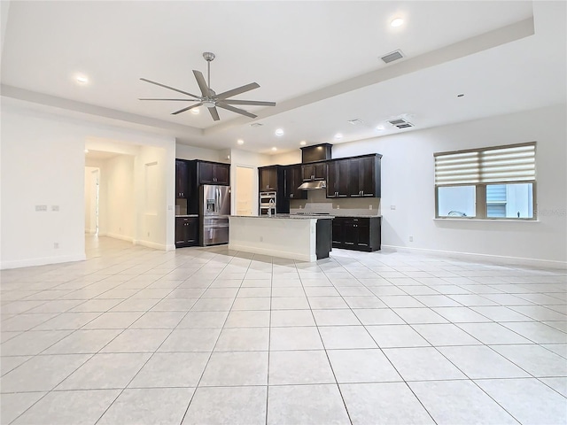 kitchen with appliances with stainless steel finishes, open floor plan, a ceiling fan, and light countertops