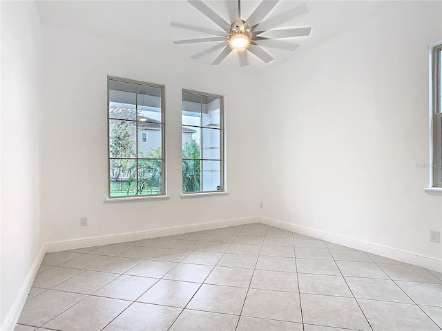 empty room with ceiling fan, baseboards, and light tile patterned flooring