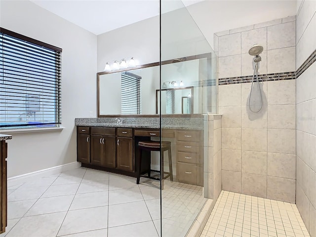 full bath featuring tile patterned flooring, walk in shower, vanity, and baseboards