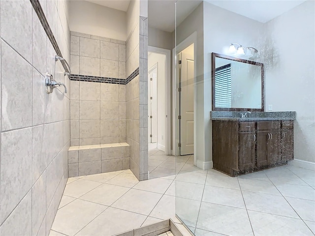 full bath featuring tile patterned flooring, tiled shower, vanity, and baseboards